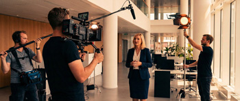 Équipe de production vidéo réalisant un reportage d'entreprise sur le terrain, avec caméra et éclairage, pour présenter une activité.