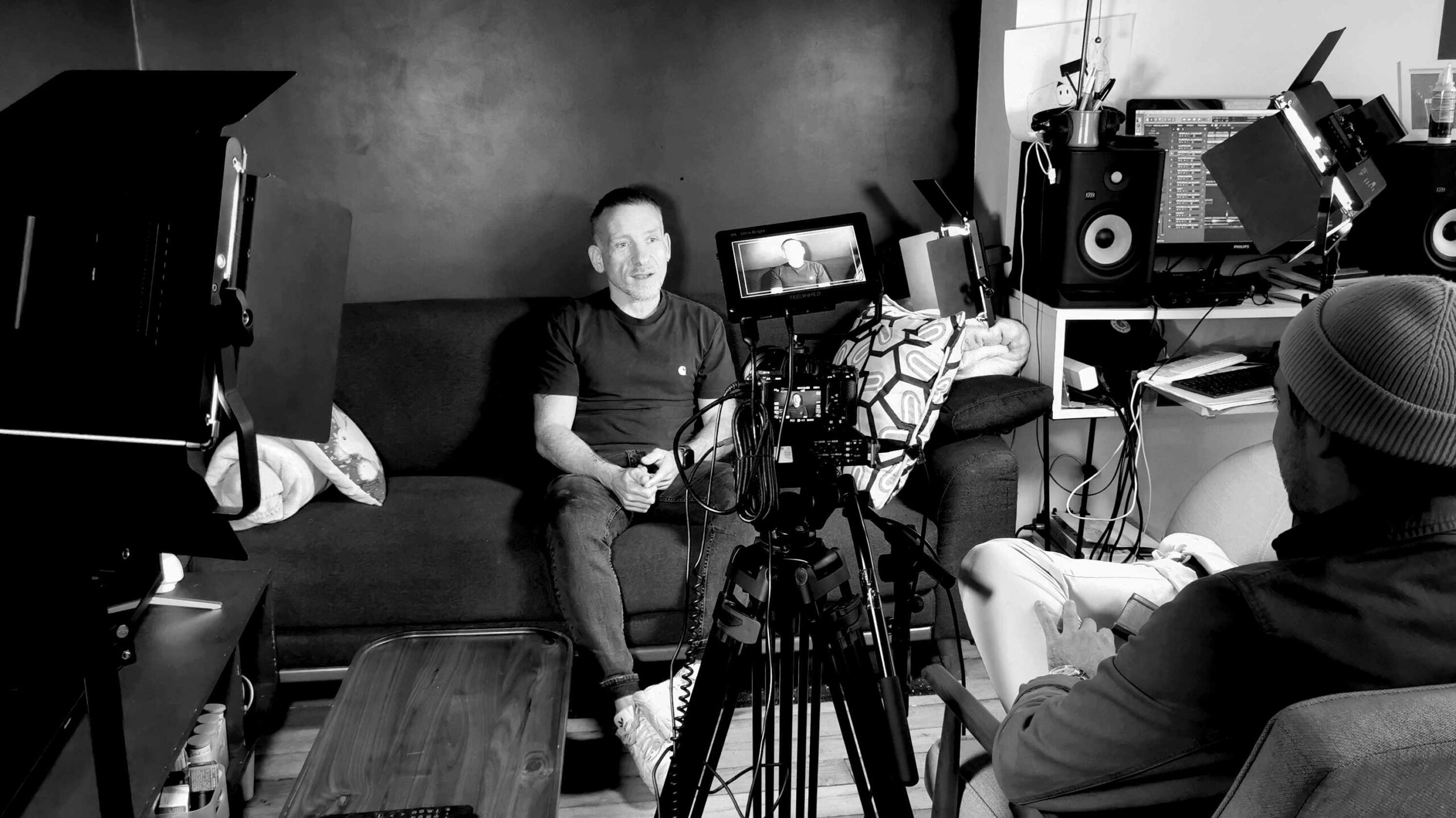 Coulisses d’un tournage d’interview avec un intervenant, une caméra et l’équipe de réalisation.